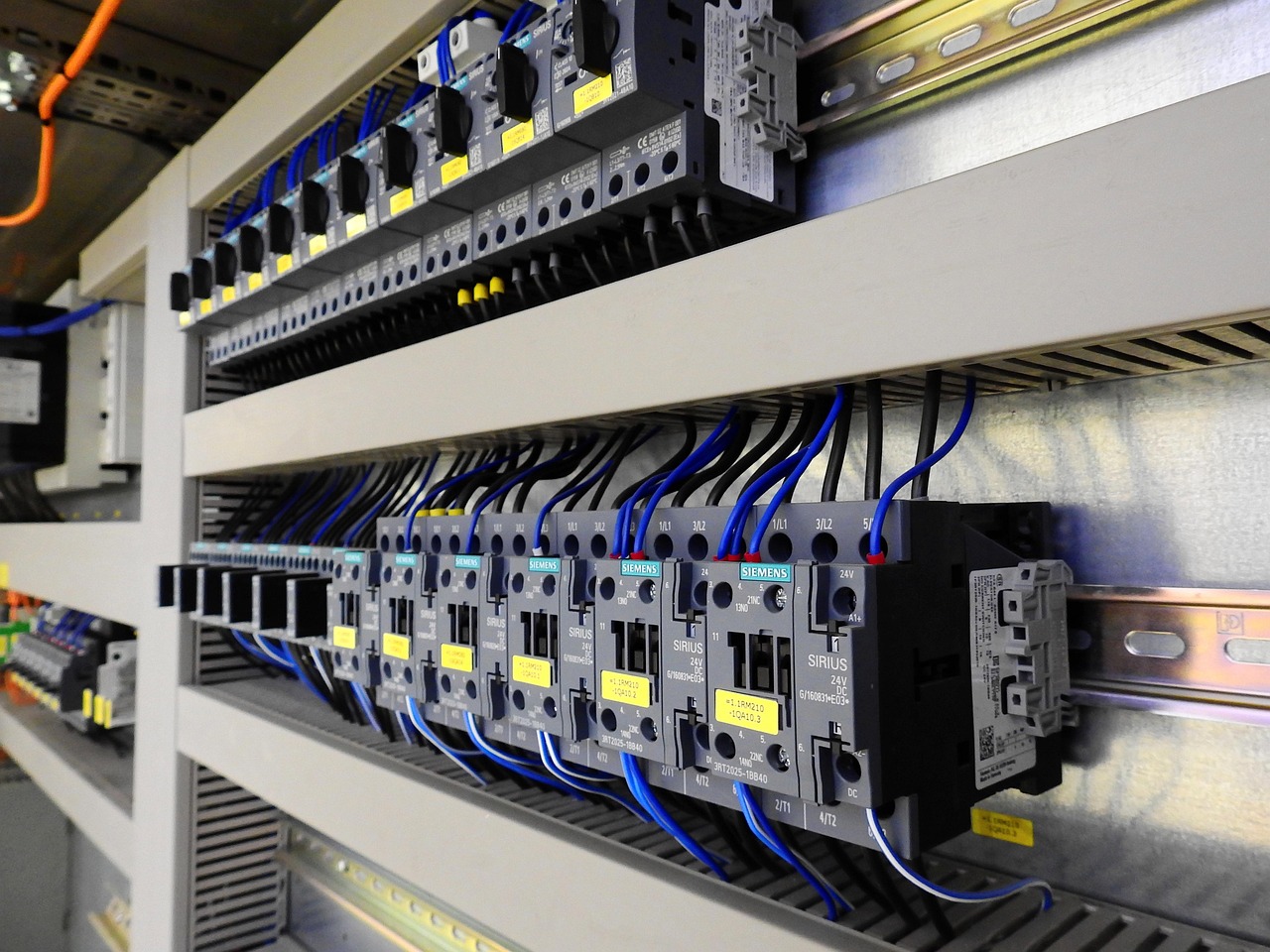 Industrial switch cabinet with rows of contactors, motor protection switches and blue control wiring
